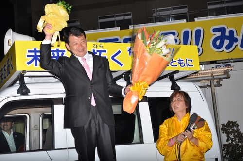 花束を手に支援者に当選の喜びを伝える小野氏（左）＝広野の事務所（２１日午後１０時３２分撮影）