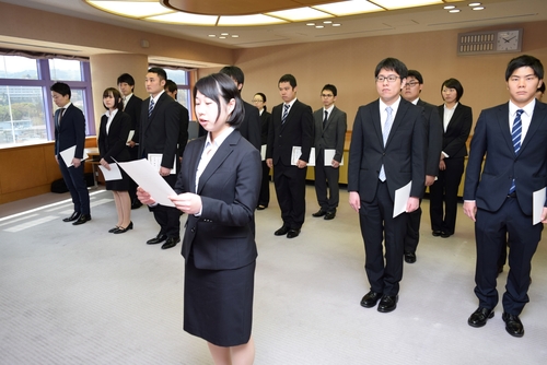 新規採用職員を代表して宣誓書を読み上げる長谷川さん（中央）＝市役所