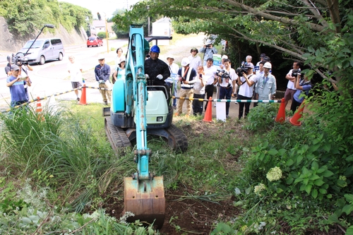 計画に反対する住民らの前で重機を使った整地作業を進める工事関係者＝八幡野