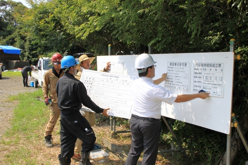 造成工事や林地開発の許可などに関する看板を設置する工事関係者＝八幡野