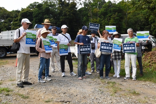 プラカードを掲げて事業者に抗議する反対住民たち＝八幡野