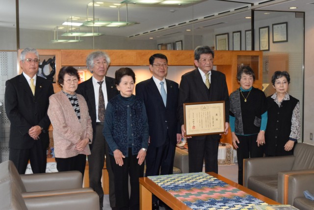 小野市長と記念撮影する県知事褒賞の久保田さん（右から３人目）ら＝伊東市役所