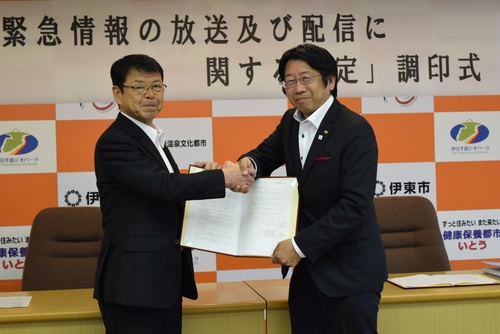 協定書を持ち握手する小野市長（左）とＩＫＣの比企社長＝市役所