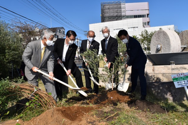 ２０本目となるオリーブの木を植える（左から）水口会長、小野市長ら＝伊東市渚町のリエティ広場