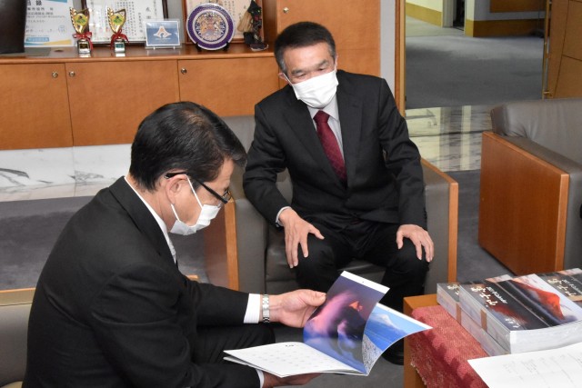 小野市長（左）にカレンダーの写真について説明する筒井さん＝伊東市役所