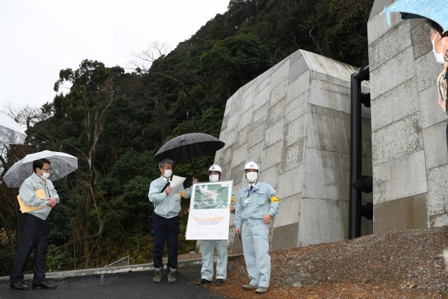 県熱海土木事務所の担当者から完成した「石脇沢砂防堰堤」の説明を受ける小野市長（左）＝伊東市八幡野