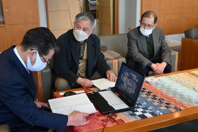 小野市長（左）に史料集の説明をする西島会長（中央）＝伊東市役所