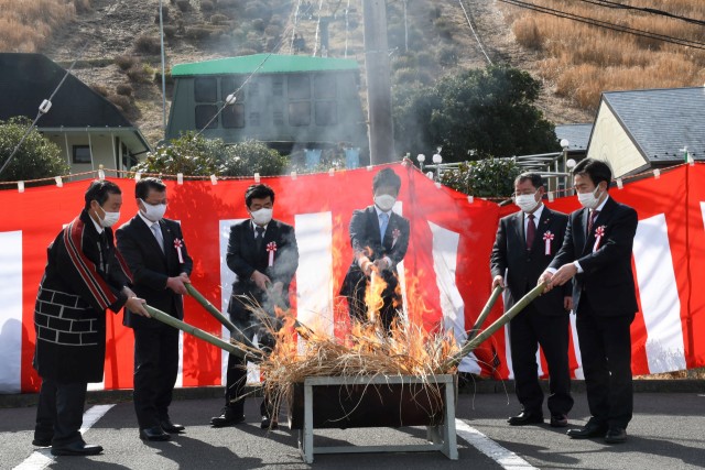 「採火式」で事前に採集したカヤにたいまつで点火する来賓ら＝伊東市の大室山リフト第２駐車場